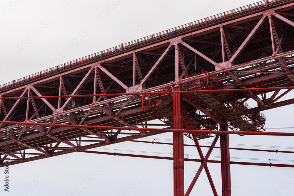 Detail view of red steel beam suspension bridge in overcast