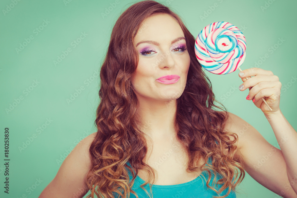 Smiling girl with lollipop candy on teal