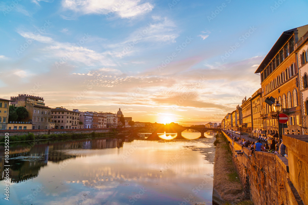 Sunset over Arno river in Florence, Italy. Spectacular sky, medieval bridge and buildings.