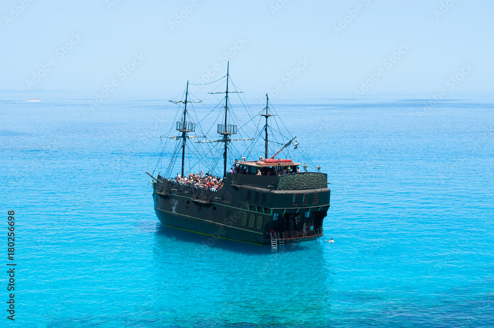 Black pirate ship on the blue sea. Back view Black pirate ship on the blue sea. Back view
