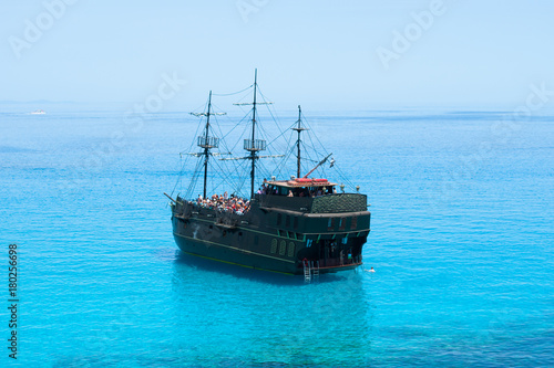 Black pirate ship on the blue sea. Back view