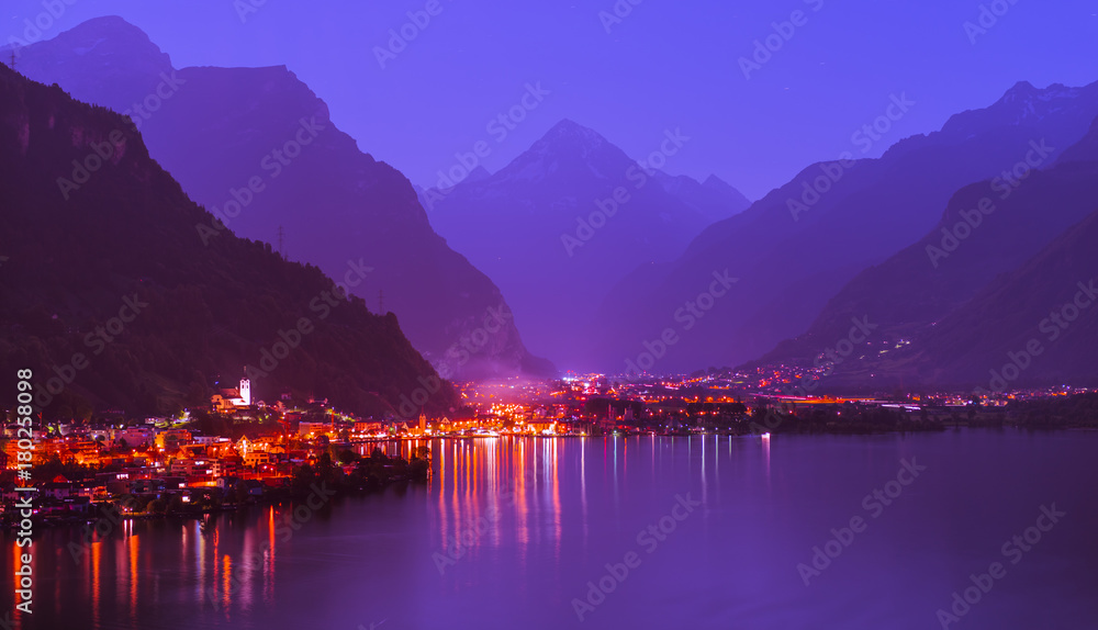 Lights of the night city. Switzerland. Night panorama of a small town in the Alps.  The village  in the foreground. Lake Uri. Mountain range in the direction of Italy.