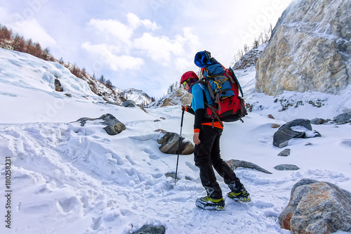 Female mountaineer with backpack, helmet and harness with climbing in mountain photo