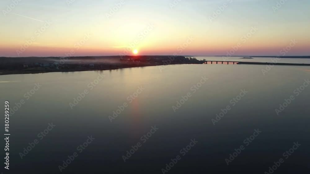 4K. Flight over large frozen lake with bridge in winter on sunset, aerial view. 4K. Flight over large frozen lake with bridge in winter on sunset, aerial view.