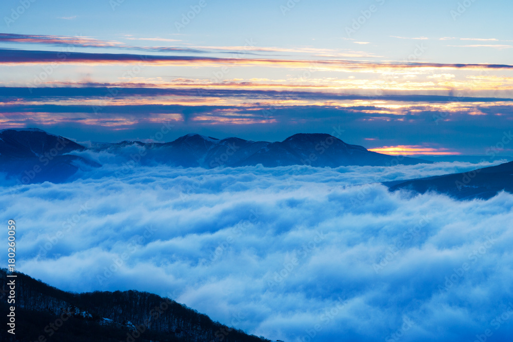 Sunrise in the mountains. The peaks of the mountains rise above the clouds.