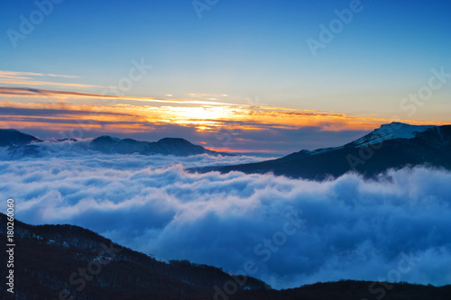 Sunrise in the mountains. The peaks of the mountains rise above the clouds.