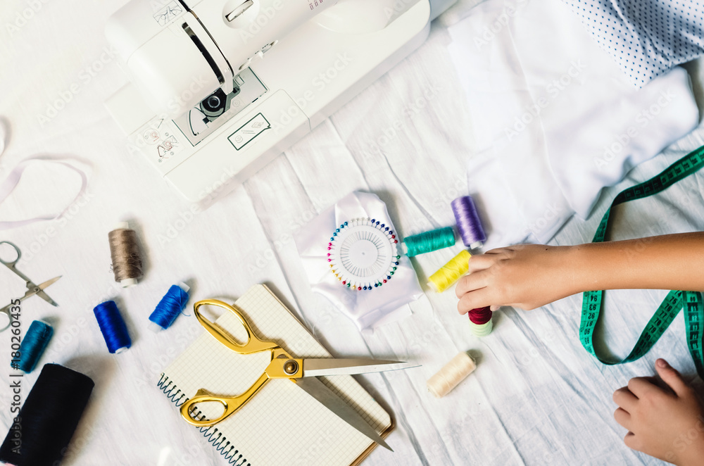 Fototapeta premium process of sewing work. preparation for needlework. thread, machine, centimeter, scissors, notepad, hairpins, needles, cloth