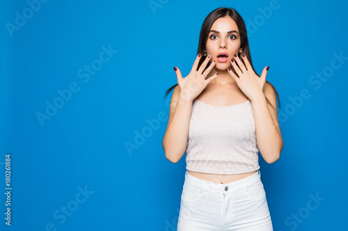 Close up portrait of a happy excited young woman with mouth open looking at camera isolated over blue background