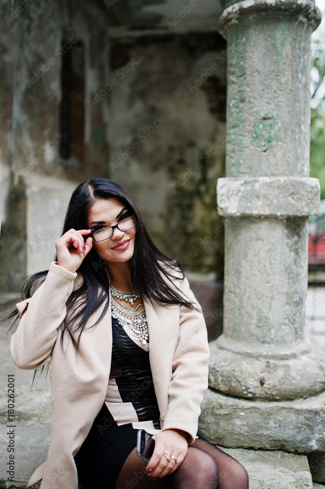 Black hair sexy woman in glasses and coat posed at street of old city. Black hair sexy woman in glasses and coat posed at street of old city.