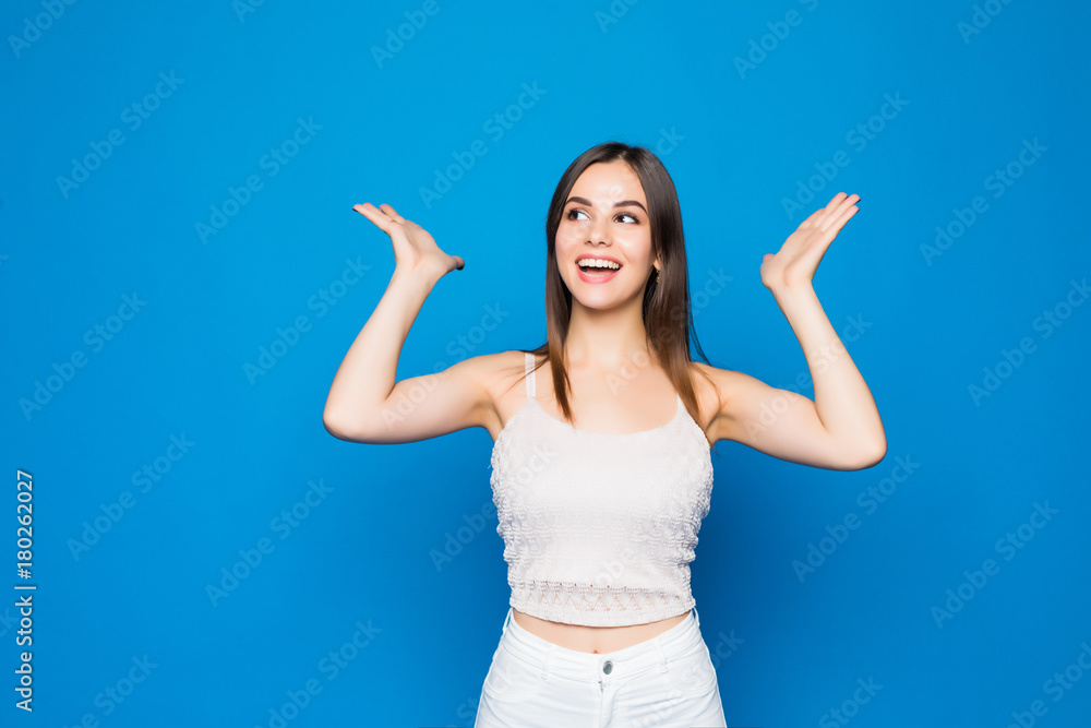 Fototapeta premium Close up portrait of a happy excited young woman with mouth open isolated over blue background