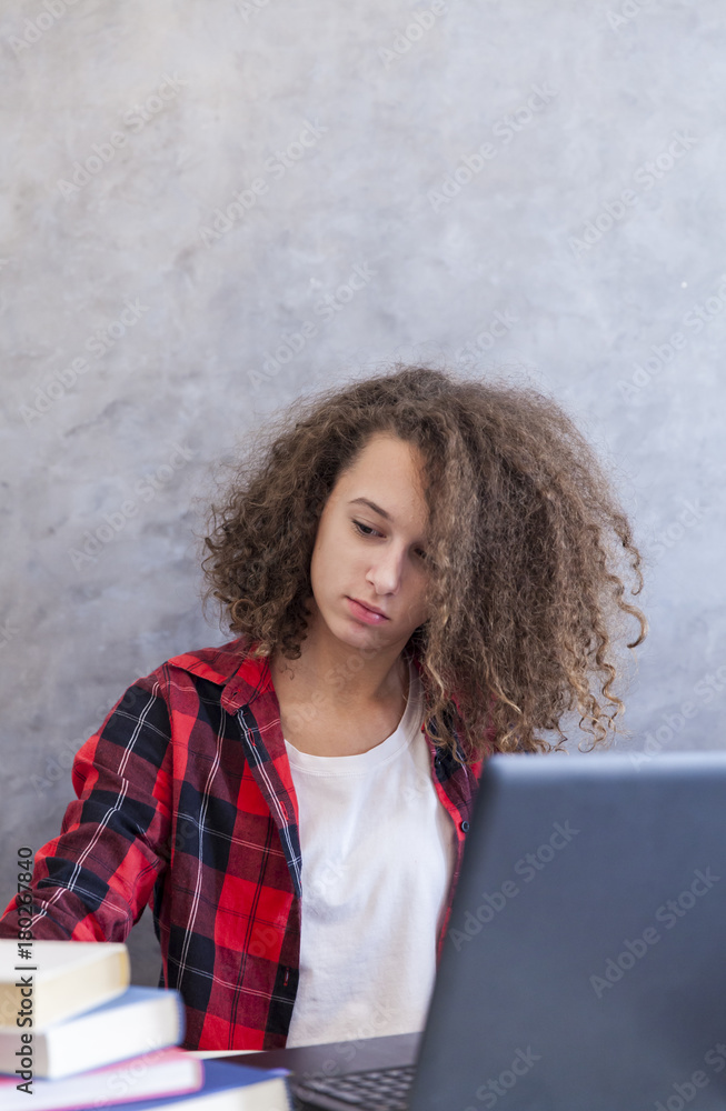 Φωτογραφία Curly hair teen girl websurfing internet on laptop at home