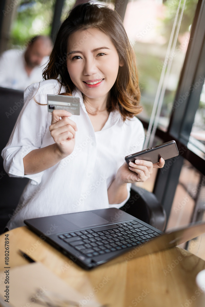 Obraz premium business asian girl in white shirt with credit card and smartphone onine shopping ideas concept with background of blur image coffeeshop