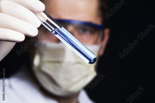 chemist looks at test tube with blue liquid in his hands