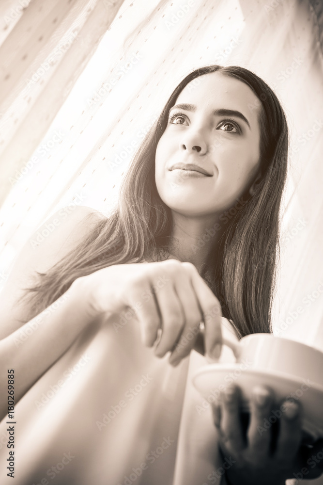 Naklejka premium beautiful happiness caucasian girl enjoy morning moment with hot coffee in white tshirt with light from white curtain