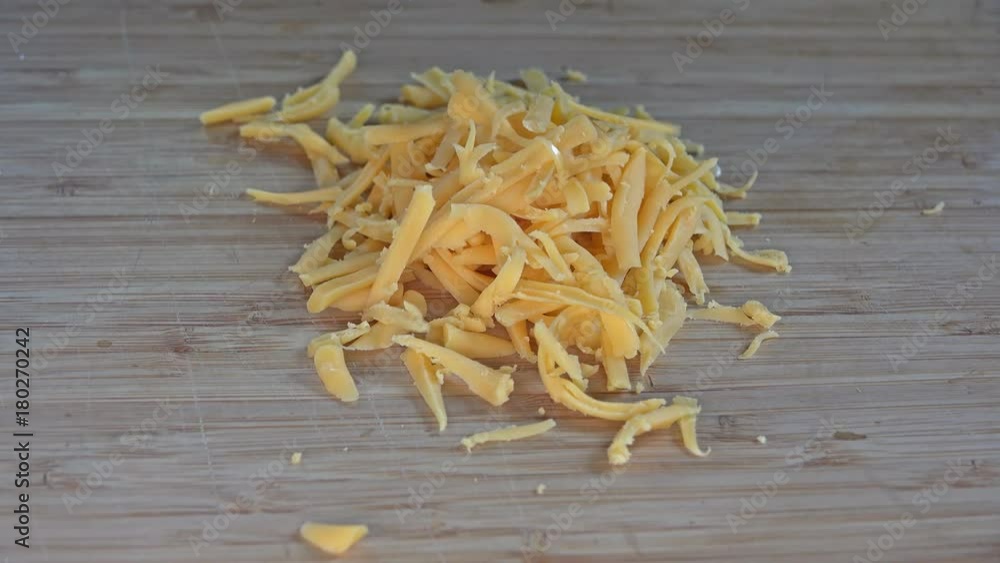 Grated cheddar cheese falling to a cutting board, 4k Grated cheddar cheese falling to a cutting board, 4k
