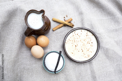postre de natillas con los ingredientes como azúcar,leche,huevos y canela photo