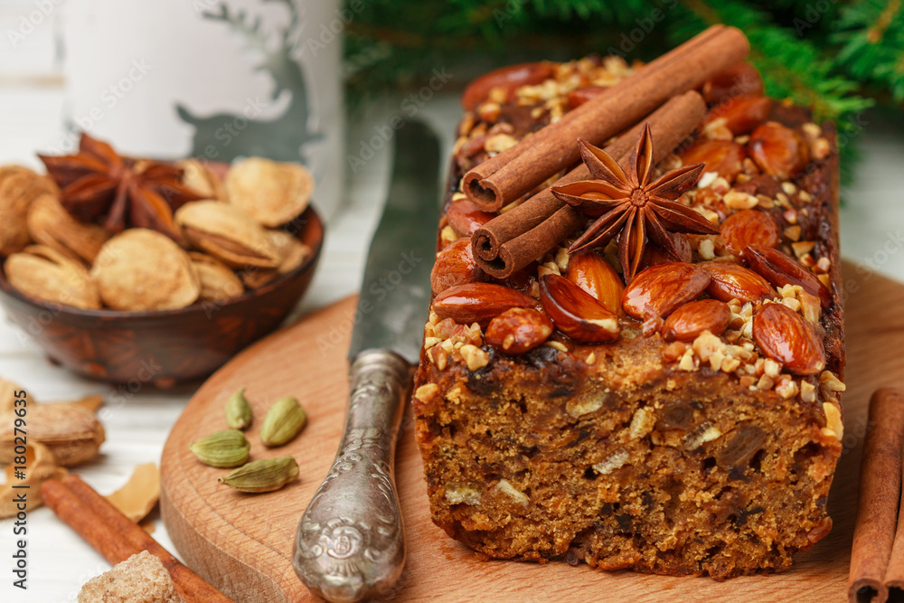 Homemade holiday Fruitcake with nuts, fruits and spices. Almonds, cinnamon, star anise, cardamom on the table. Traditional English pastries. Christmas. New year. Selective focus Homemade holiday Fruitcake with nuts, fruits and spices. Almonds, cinnamon, star anise, cardamom on the table. Traditional English pastries. Christmas. New year. Selective focus