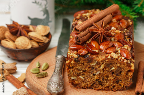 Homemade holiday Fruitcake with nuts  fruits and spices. Almonds  cinnamon  star anise  cardamom on the table. Traditional English pastries. Christmas. New year. Selective focus