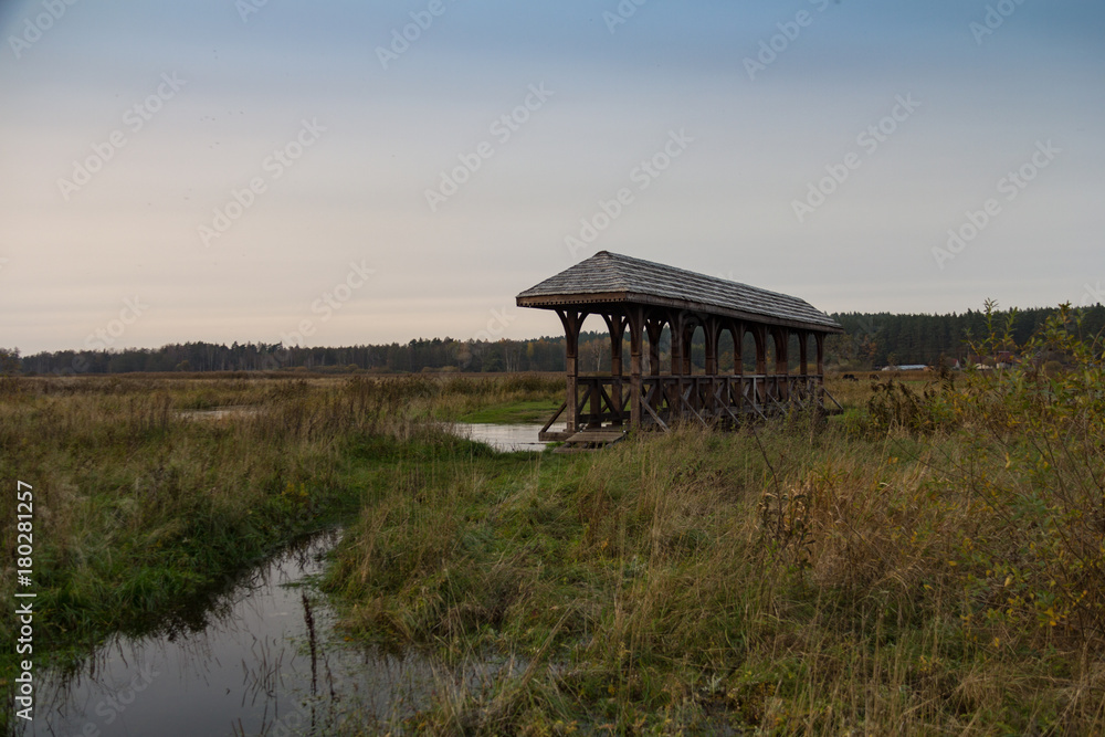 A wooden covered bridge over the river in the autumn sun A wooden covered bridge over the river in the autumn sun