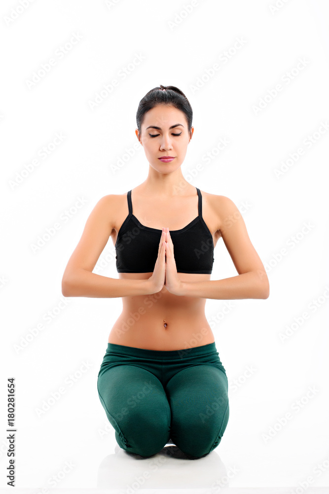 Fototapeta premium Beautiful young woman practicing yoga with namaste, meditating, breathing, relaxing; sitting in the prayer position