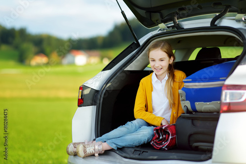 Adorable little girl ready to go on vacations with her parents. Child relaxing in a car before a road trip.