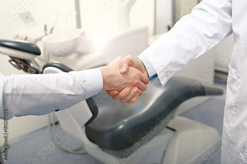 A dentist and a patient are handshaking