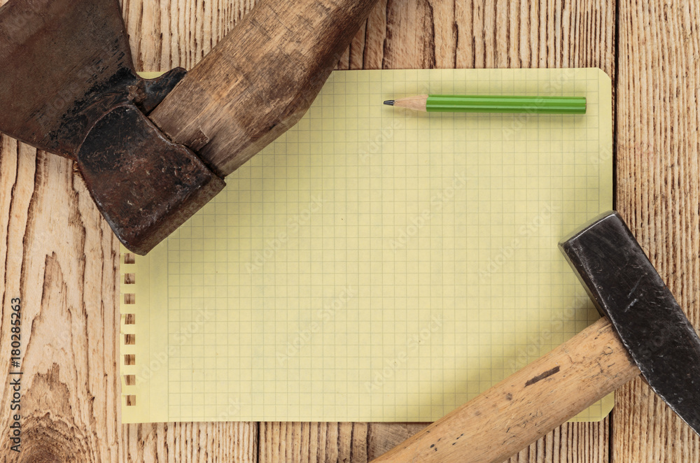 Old carpentry tools and a piece of notebook on a wooden background Old carpentry tools and a piece of notebook on a wooden background