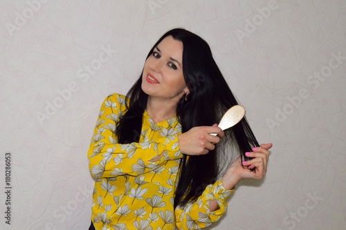 the young, beautiful woman brushes hair by means of a crest. The woman is located on a white background photo