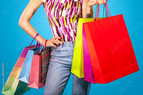 Black friday holiday. Woman at shopping holding bags isolated on blue background.. Copy space for sale.