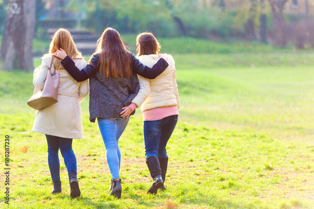 Fototapeta premium Three female friends walking in park