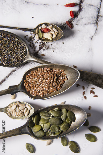 Food ingredients in old steel spoon on marble background. Flax, pumpkin seed, sunflower seed and sesame. healthy food concept