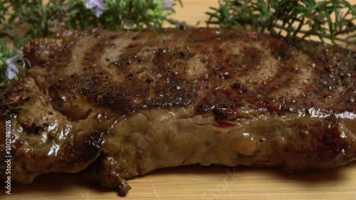 Grilled Ribeye Steak Being Placed on a Wooden Cutting Board to Rest. Closeup Macro Footage. photo