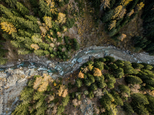 Aerial view of river flowing through forest in alpine valley in Switzerland