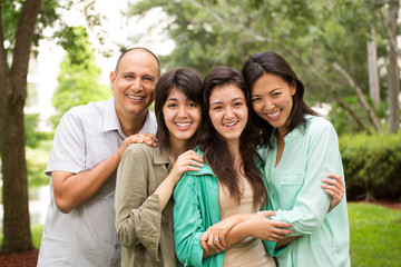 MIxed race family laughing and huging.