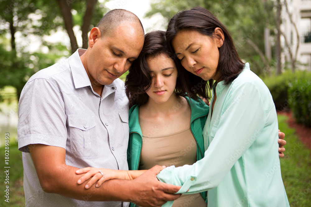 Portrait of a family praying with their daughter. Portrait of a family praying with their daughter.