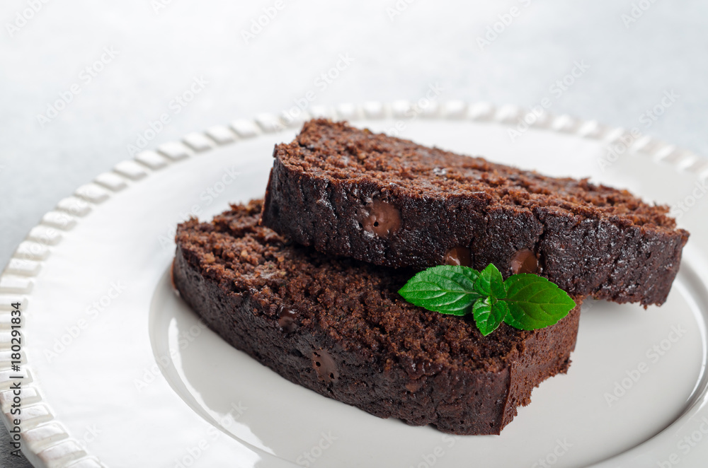 Two slices of chocolate cake with mint leaves served on a white Two slices of chocolate cake with mint leaves served on a white