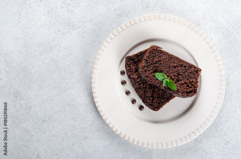 Two slices of chocolate cake with mint leaves served on a white Two slices of chocolate cake with mint leaves served on a white