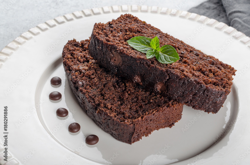 Two slices of chocolate cake with mint leaves served on a white Two slices of chocolate cake with mint leaves served on a white