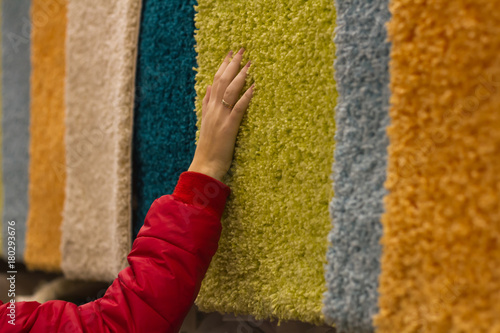 Woman spends shopping and selects plush carpets by hand in the store
