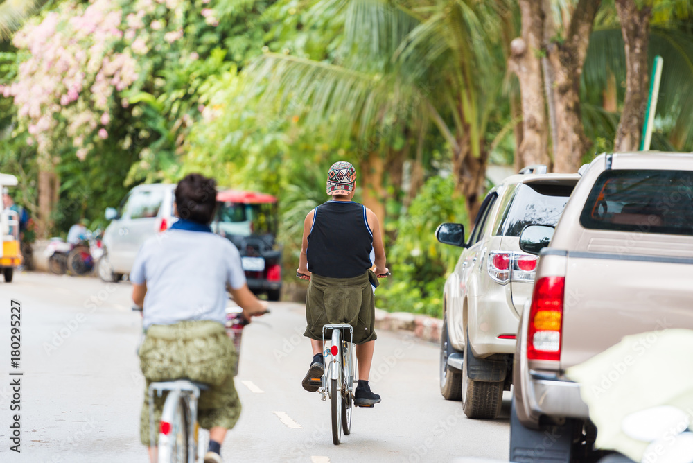 People on bicycles on a city street  in Louangphabang, Laos. Copy space for text.