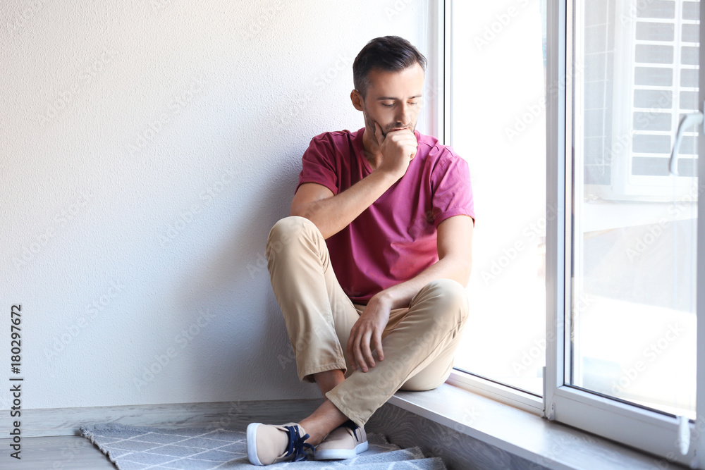 Fototapeta premium Depressed man sitting near window