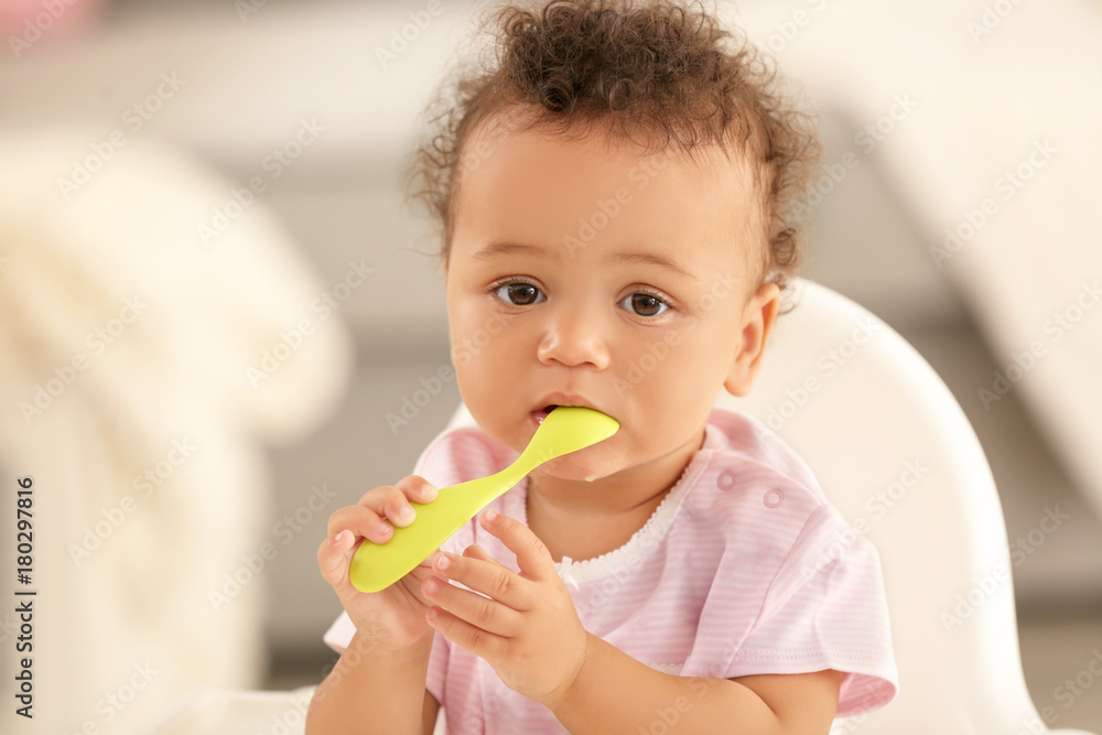 Cute baby with spoon sitting in room Cute baby with spoon sitting in room