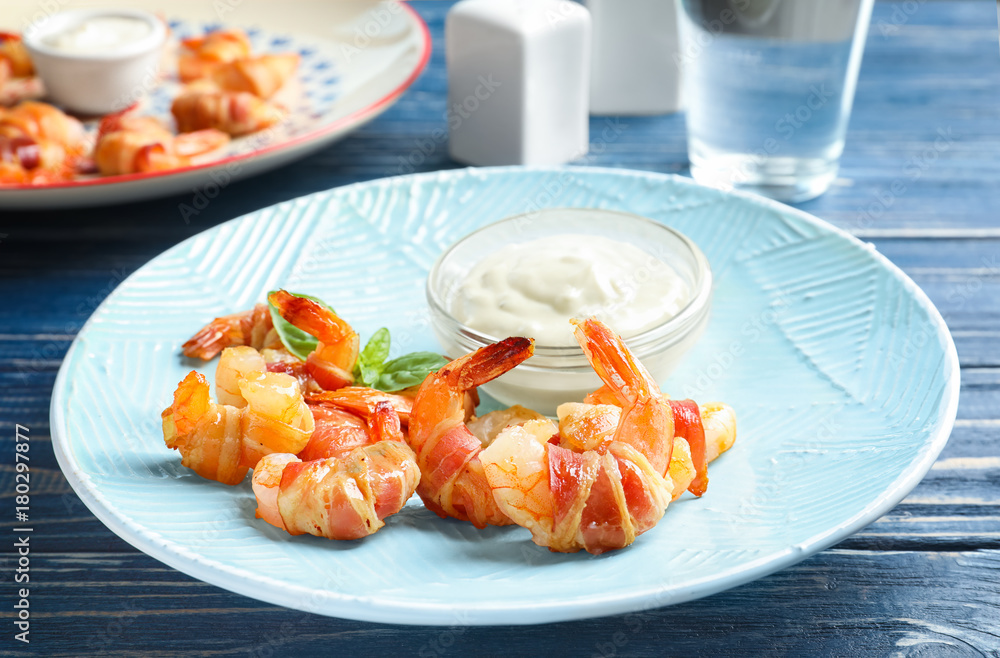 Plate with shrimps wrapped in bacon and sauce on table Plate with shrimps wrapped in bacon and sauce on table