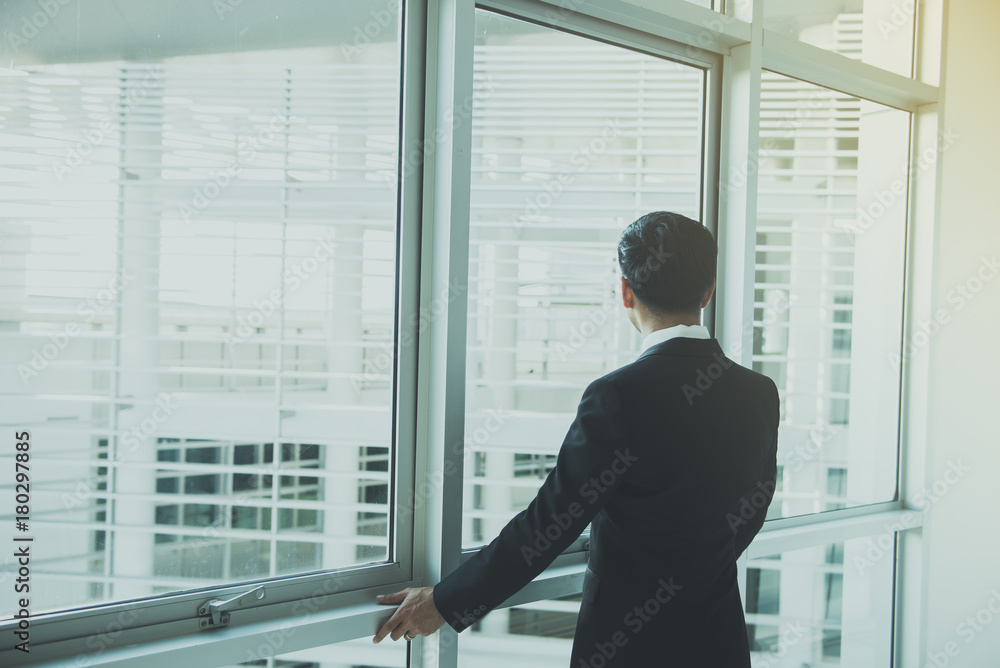 Fototapeta premium Portrait Asian businessman in black suit on the building from back angle,thailand people