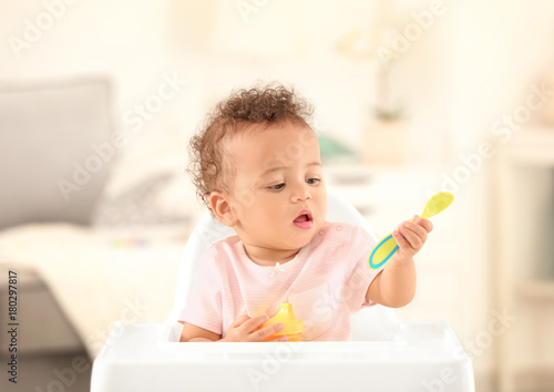 Cute baby with spoon sittin...