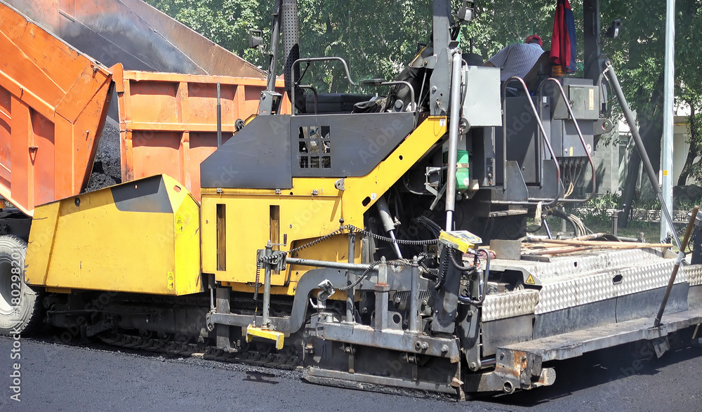 Road construction. Applying new hot asphalt using road construction machinery and power industrial tools. Roadworks repaving process. Road construction. Applying new hot asphalt using road construction machinery and power industrial tools. Roadworks repaving process.