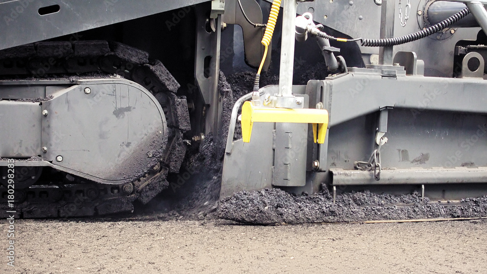 Road construction. Applying new hot asphalt using road construction machinery and power industrial tools. Roadworks repaving process. Road construction. Applying new hot asphalt using road construction machinery and power industrial tools. Roadworks repaving process.
