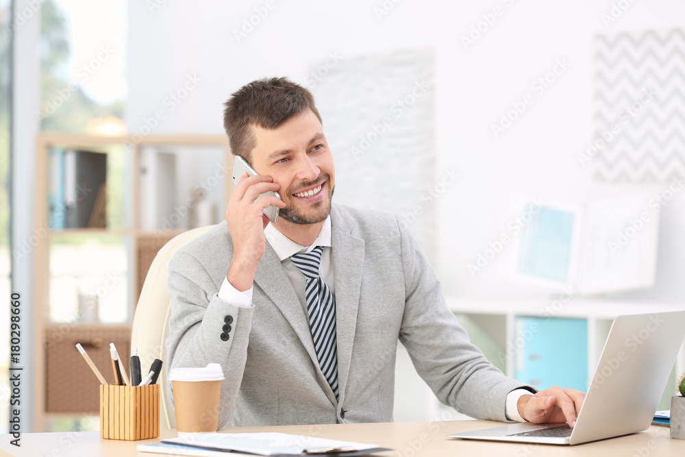 Handsome businessman talking on mobile phone while working in office Handsome businessman talking on mobile phone while working in office