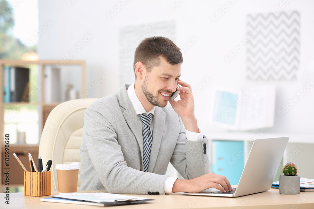 Handsome businessman talking on mobile phone while working in office Handsome businessman talking on mobile phone while working in office