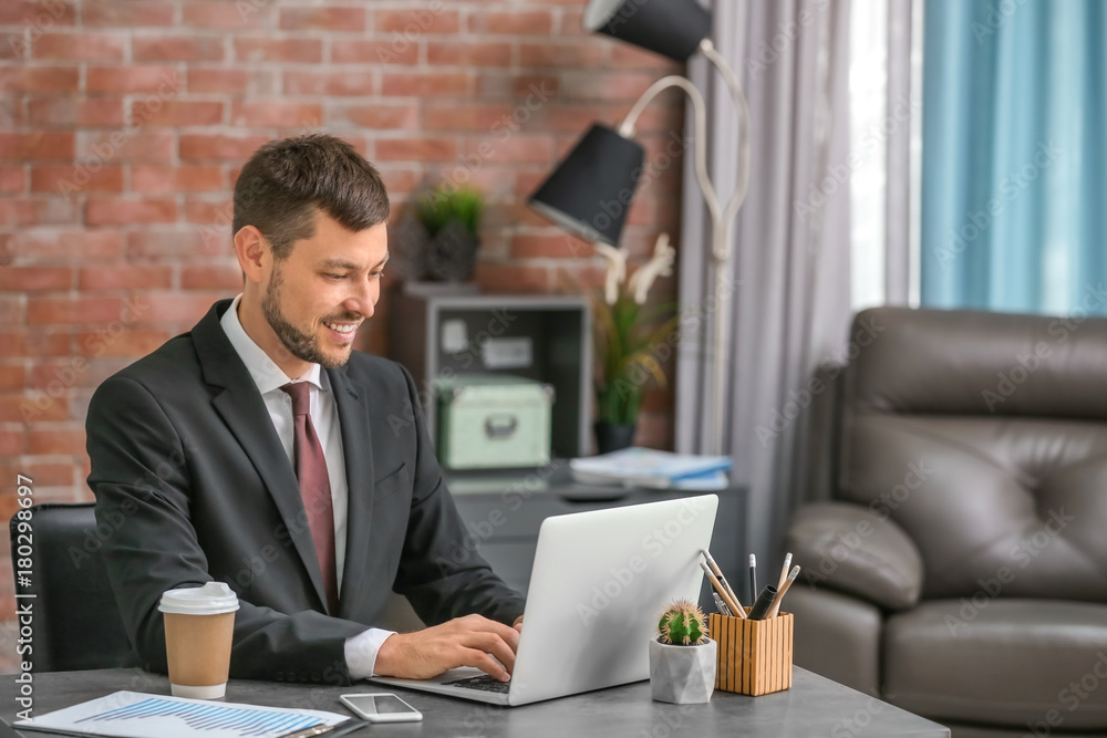 Handsome businessman using his laptop while working in office Handsome businessman using his laptop while working in office